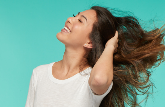 Woman waving her hair care free with a natural looking smile