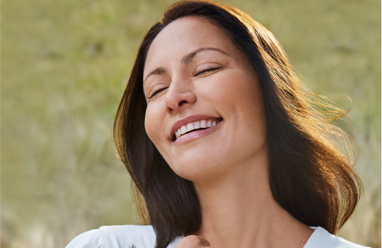 Restylane® Contour patient smiling naturally in an open meadow 